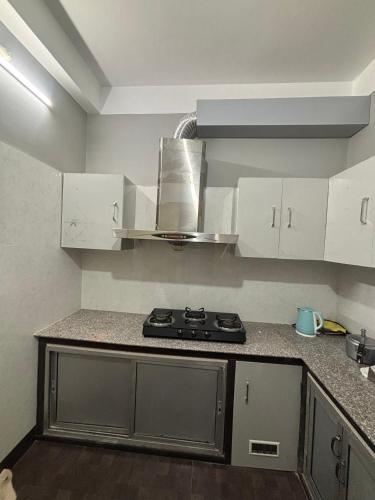 a kitchen with a stove and white cabinets at Newa House Homestay in Siliguri
