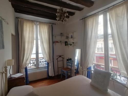 une chambre avec un lit et deux grandes fenêtres dans l'établissement Cœur de Paris Montorgueil - Heart of Paris - Charming super central apartment for your ideal Parisian days, à Paris