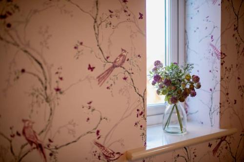 a vase of flowers sitting on a window sill next to a window with at Augusta House - Andover in Enham-Alamein