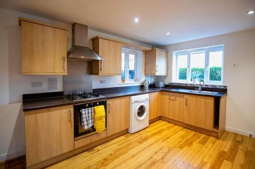 a kitchen with wooden cabinets and a washer and dryer at Augusta House - Andover in Enham-Alamein