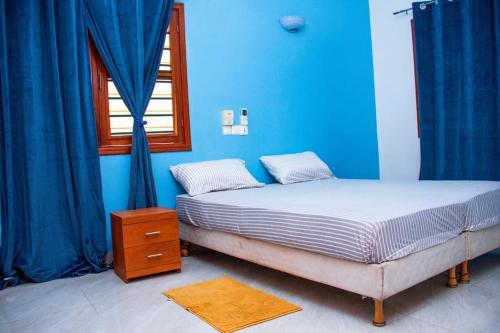a bedroom with a bed with blue walls and a window at Appartement meublé de standing - 2 Chambres in Abomey-Calavi