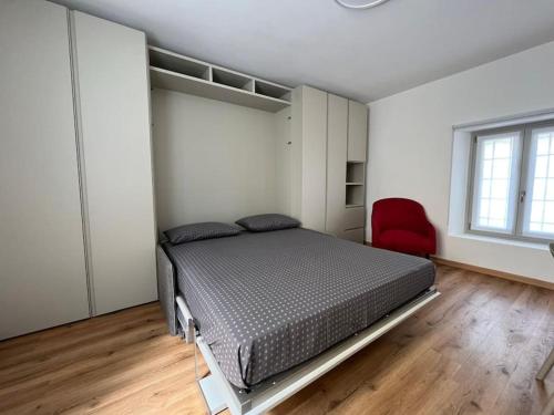 a bedroom with a bed and a red chair at Monolocale centro storico in Novara