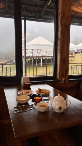 a table with a tea set on it with two windows at Ethno complex Ala kuch in Kaindy