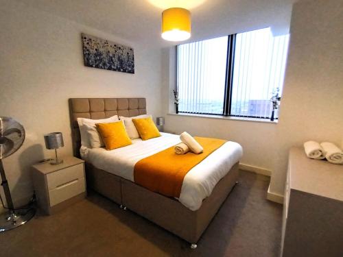 a bedroom with a bed with yellow pillows and a window at Broad St 1-Bed Sleeps 2 with Free Parking in Birmingham