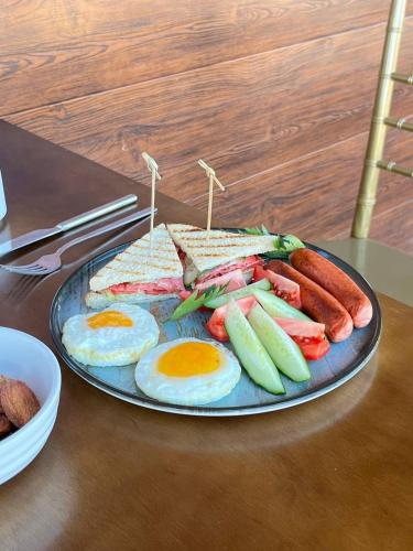 a plate of breakfast food with eggs sausage and vegetables at Ethno complex Ala kuch in Kaindy