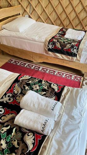 two beds with towels on them in a room at Ethno complex Ala kuch in Kaindy