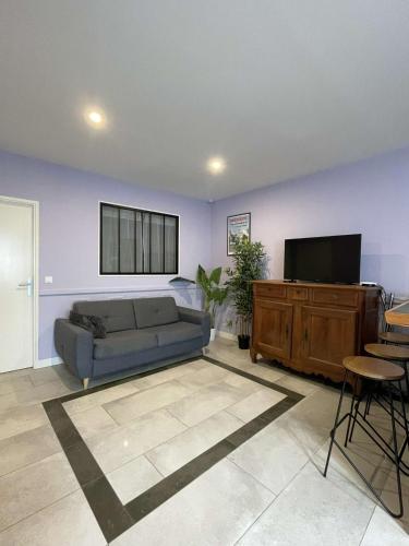 a living room with a couch and a flat screen tv at Une nuance de fantaisie in Angoulême