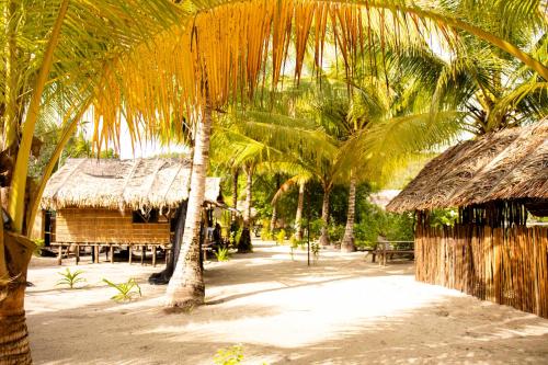 a resort with palm trees and tables and a building at manyaifun guest house in Minyaifuin