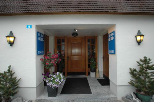 a front door of a house with flowers and plants at Hotel Pension Im Dorf in Zuzwil