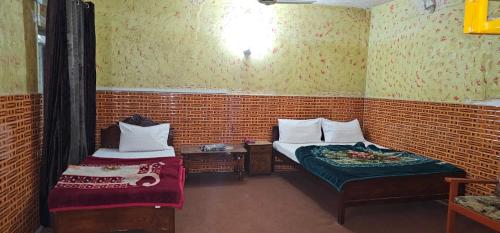 a small room with two beds and a table at Zain Hotel Abbottabad in Abbottabad