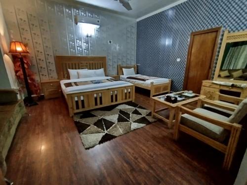 a large room with two beds and a table at Alaf Laila Guest House in Abbottābād