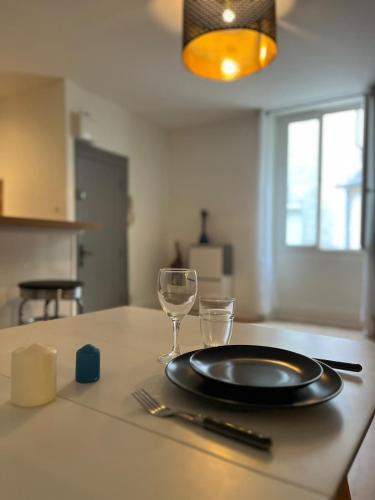 - une table avec une assiette et des verres à vin dans l'établissement Halle aux Blés- Appartement au Centre Historique, à Bourges