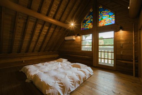 a large bed in a room with a stained glass window at log&sauna 和 - nagomi, wakayama - in Kinokawa