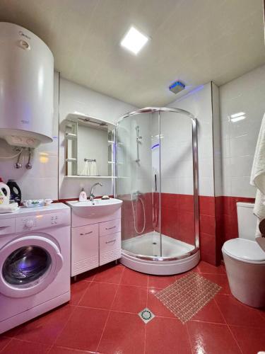 a bathroom with a shower and a washing machine at Apartment Rimma in Batumi