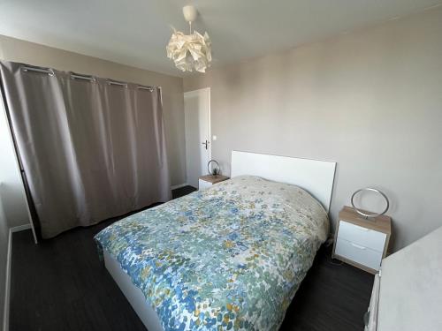 une chambre avec un lit et un lustre dans l'établissement Azur et vagues, à Barfleur