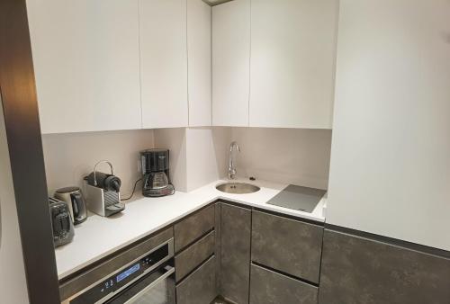a small kitchen with white cabinets and a sink at MyHome - Curling A3 15 - Très beau 2 pièces 4pax skis aux pieds - Val Claret in Tignes