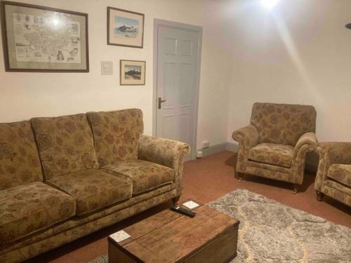 a living room with a couch and two chairs at Quaint Cottage main street Llandeilo in Llandeilo
