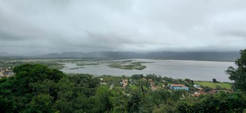 a large body of water with trees and a town at Pousada Jardim da Lagoa in Garopaba