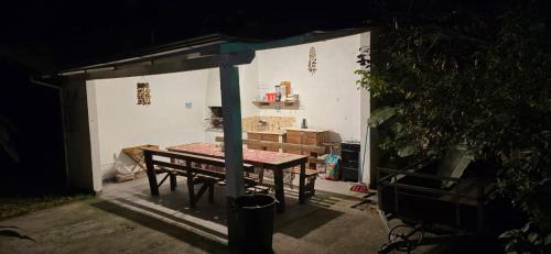 a table and a bench in a shed at night at Pousada Jardim da Lagoa in Garopaba
