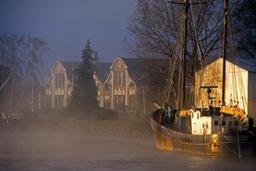 a boat sitting in the water in front of a house at Hotel Naguilan in Valdivia