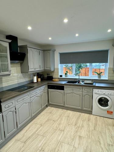 a kitchen with white cabinets and a dishwasher at Florina s House 4 Bedrooms Villa in Rugeley