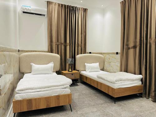 two beds sitting in a room with curtains at Art Apartments Karbala in Karbala