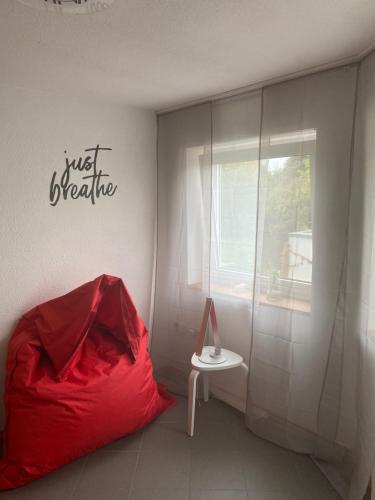 a room with a red cover and a table and a window at Gemütliche, sonnendurchflutete Ferienwohnung in Bodenseenähe am Säntisblick in Herdwangen-Schönach