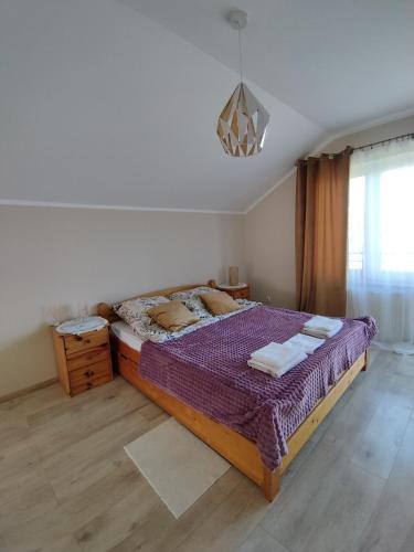 a bedroom with a large bed with a purple blanket at Urocze Apartamenty in Cięcina