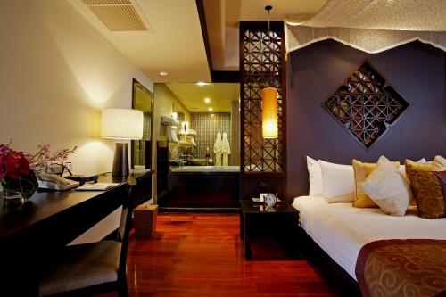 a bedroom with a bed and a desk and a bathroom at Dusit Thani Laguna Phuket in Bang Tao Beach