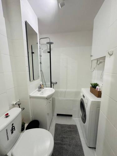 a white bathroom with a toilet sink and a washing machine at Warszawa Centralna Rooms in Warsaw