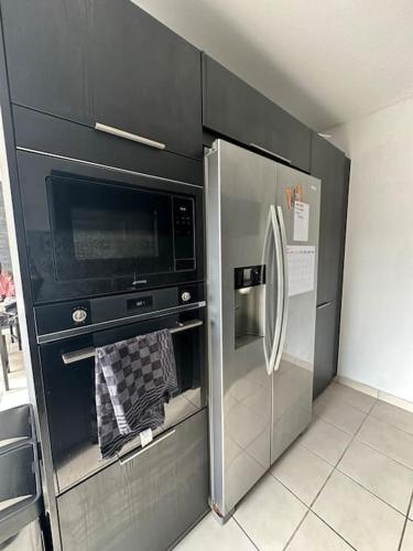 une cuisine avec un réfrigérateur en acier inoxydable et des armoires noires dans l'établissement Superbe Maison familiale, à Tours