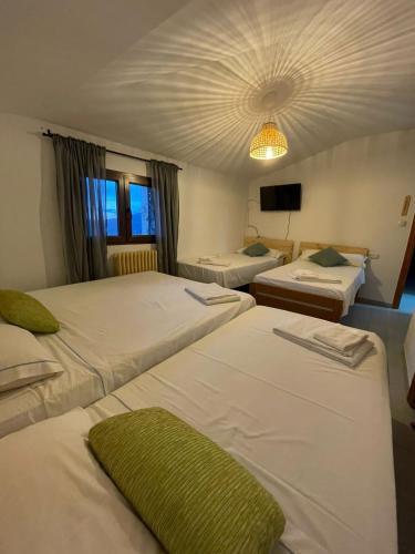 a hotel room with three beds and a television at El Refugio Valdelinares Gastro Hostal in Valdelinares