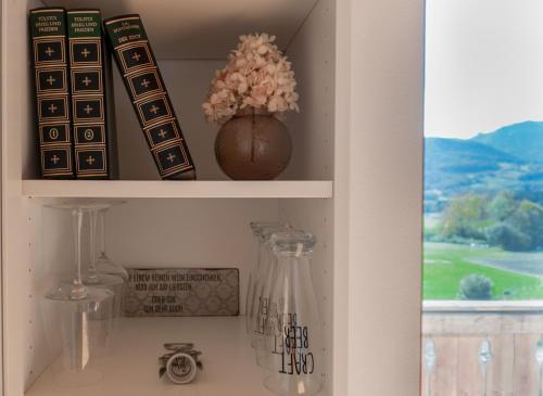 a shelf with a vase with flowers and books at Große Wohnung mit Bergblick in Frasdorf