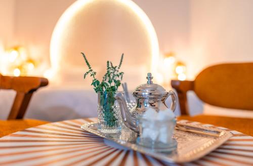 a table with a glass pitcher and a vase with flowers at Riad L'ECOLE in Marrakech
