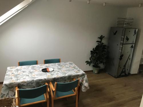a table with four chairs and a refrigerator in a room at Appartement lumineux - Bruxelles in Brussels