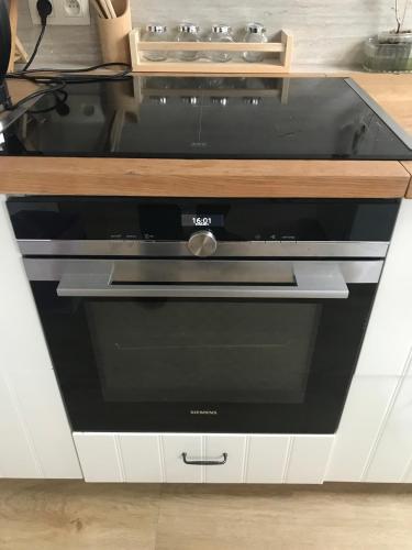 a black oven in a kitchen with white cabinets at Appartement lumineux - Bruxelles in Brussels