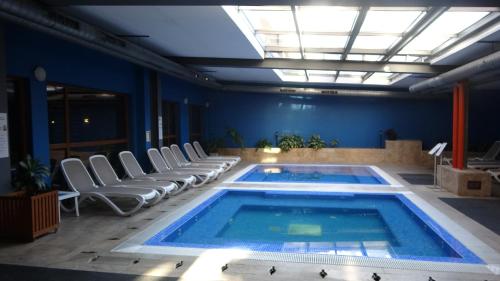 a large swimming pool with chairs and a ceiling at Mountainview Apartment Ski, Spa & Thermal in Bansko