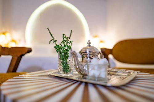 a table with a glass teapot and a vase of flowers at Riad L'ECOLE in Marrakech