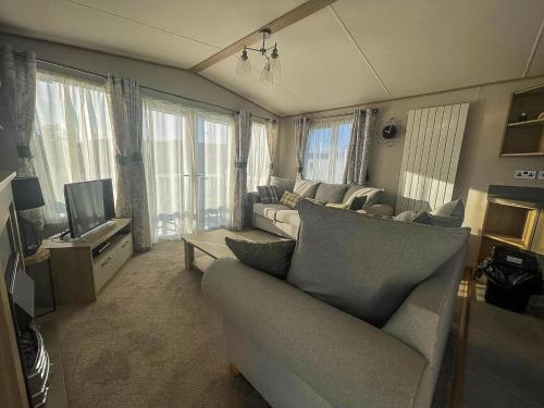 a living room with a couch and a tv at Lovely Caravan With Decking At Carlton Meres Holiday Park In Suffolk Ref 60023Ch in Saxmundham