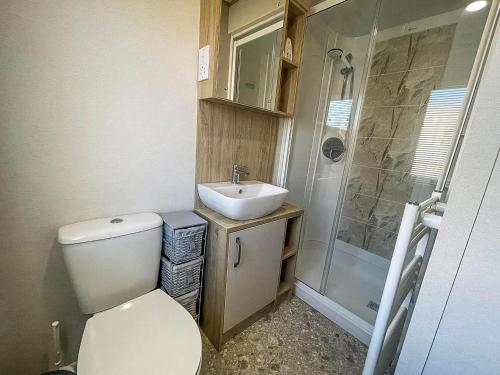 a bathroom with a toilet and a sink and a shower at Lovely Caravan With Decking At Carlton Meres Holiday Park In Suffolk Ref 60023Ch in Saxmundham