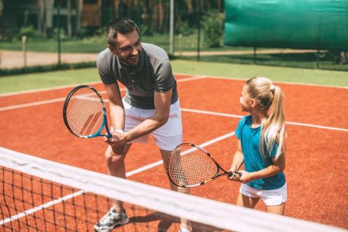a man and a girl holding tennis rackets on a tennis court at Lovely Caravan With Decking At Carlton Meres Holiday Park In Suffolk Ref 60023Ch in Saxmundham