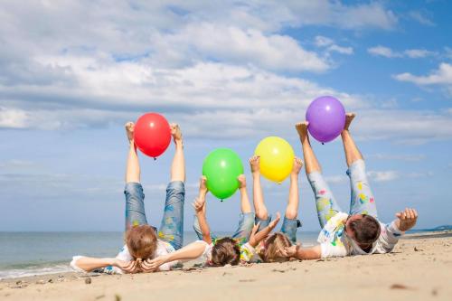 a group of children laying on the beach holding balloons at 6 Berth Pet Friendly Caravan By Hunstanton Beach, Norfolk Ref 13012L in Hunstanton