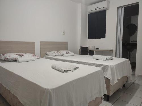 Dos camas en una habitación con paredes blancas. en Melquiades Hotel, en Patos
