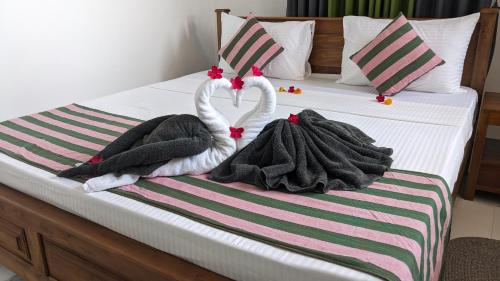 タンガラにあるStar Beach Villaの白鳥のタオル2枚がベッドの上に座っています。