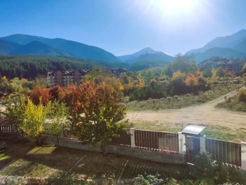 a house with a fence and mountains in the background at 7 Pools SPA Boutique Hotel in Bansko