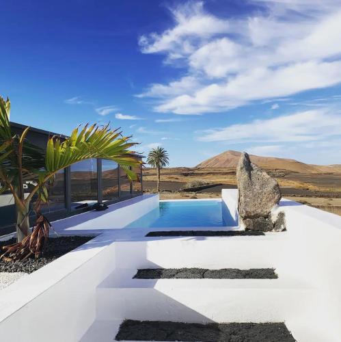 a pool in the middle of a desert with mountains in the background at Finca Marisa in Tinajo