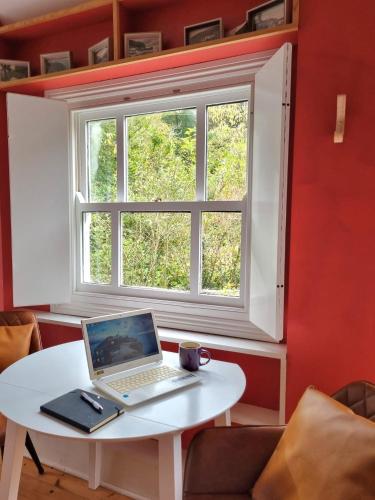 a laptop sitting on a white table in front of a window at Roses Cottage and Studio in Bideford