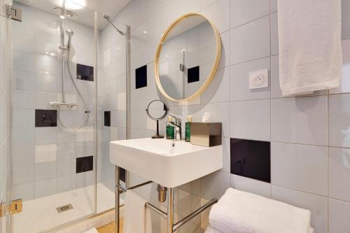a white bathroom with a sink and a mirror at Hôtel Cocoon in Saint-Ouen