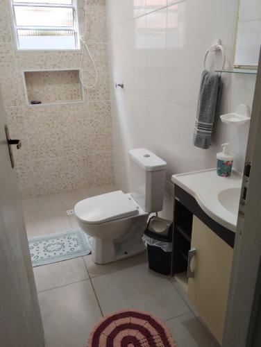 a white bathroom with a toilet and a sink at Casa na praia com piscina e churrasqueira in Itanhaém