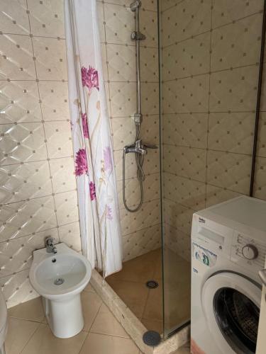 a bathroom with a shower and a toilet and a washing machine at Natali Apartments in Gjilek